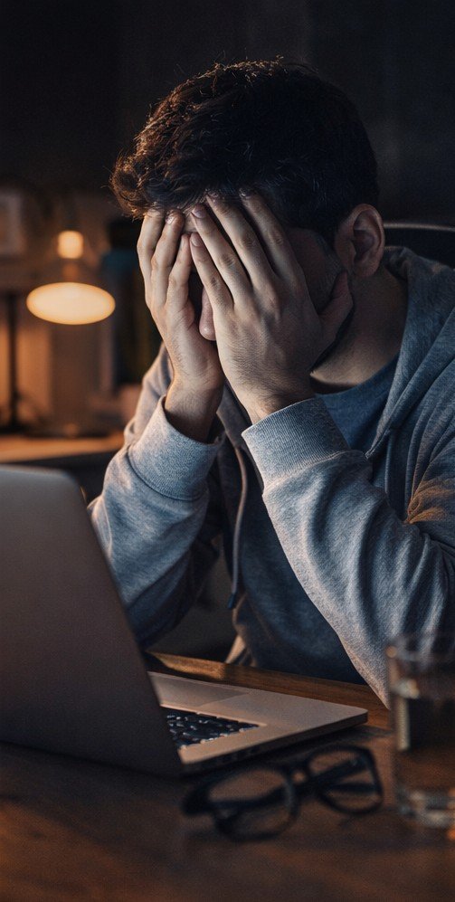 Pessoa cansada trabalhando no computador, representando cansaço mental e queda de produtividade